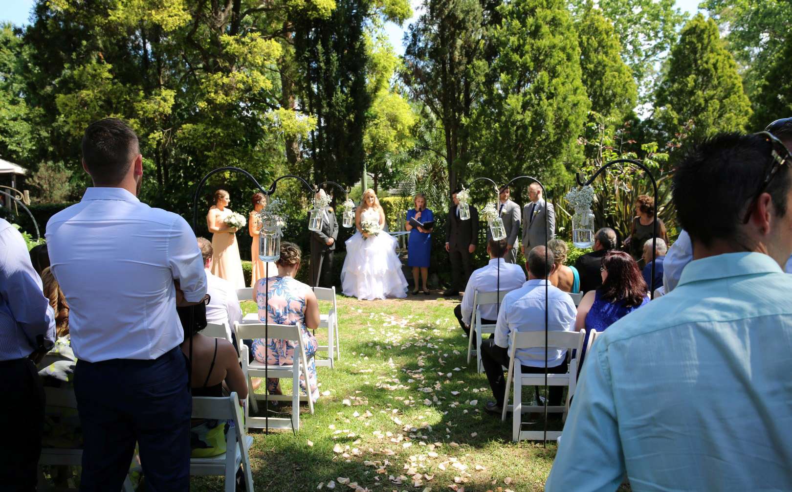 Outdoor wedding ceremony in a garden, guests seated either side of the aisle